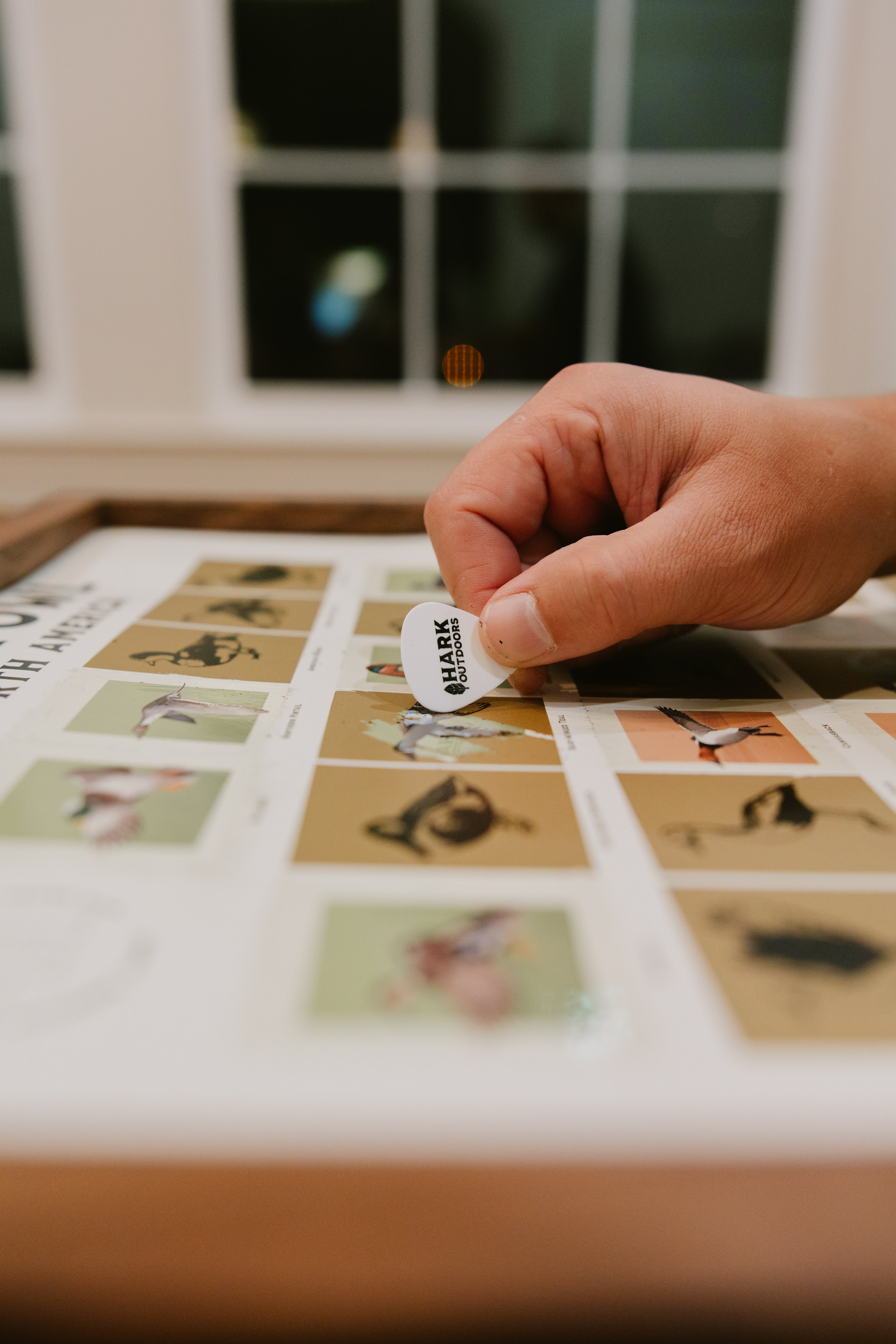 Close-up of a hand scratching off a bird species on the North American Waterfowl scratch-off hunting print.